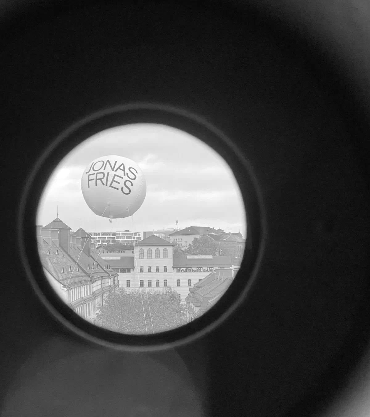 Hourglass (Strahlengänge): view through the lens of a camera obscura onto a helium balloon reading Jonas Fries above the Francke Foundations in Halle